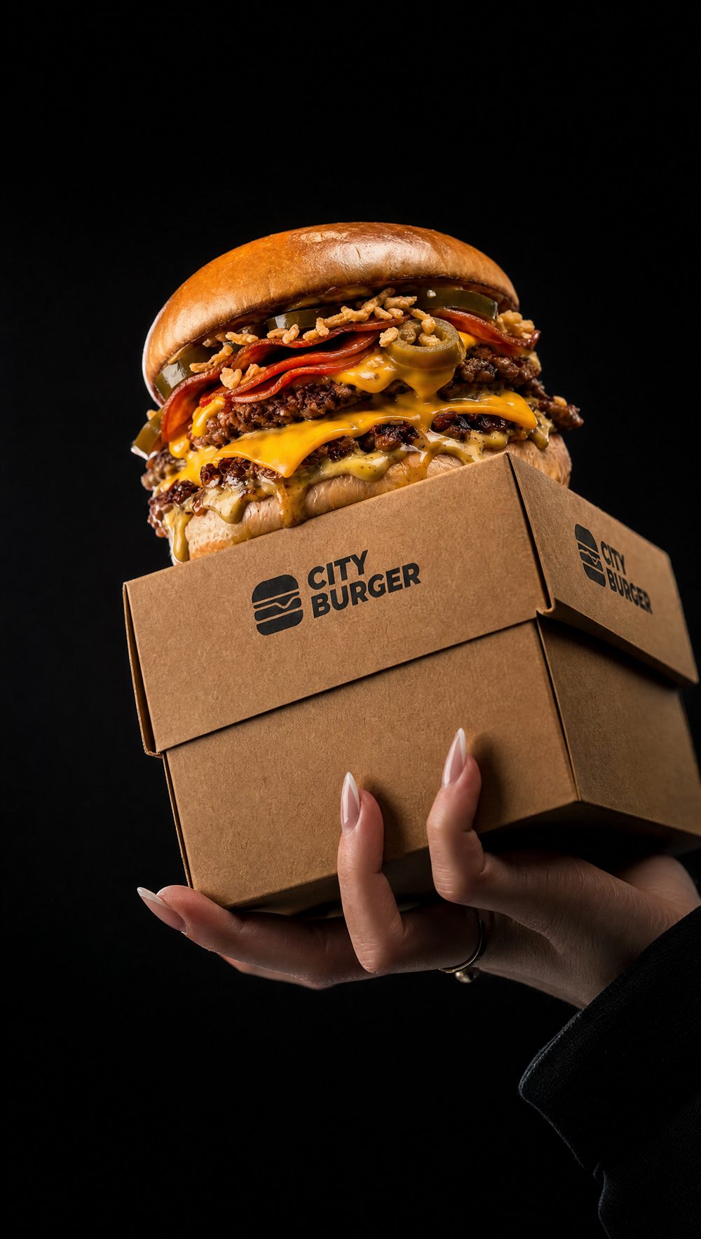 Burger CITY BURGER nad firmowym boxem, w dłoni